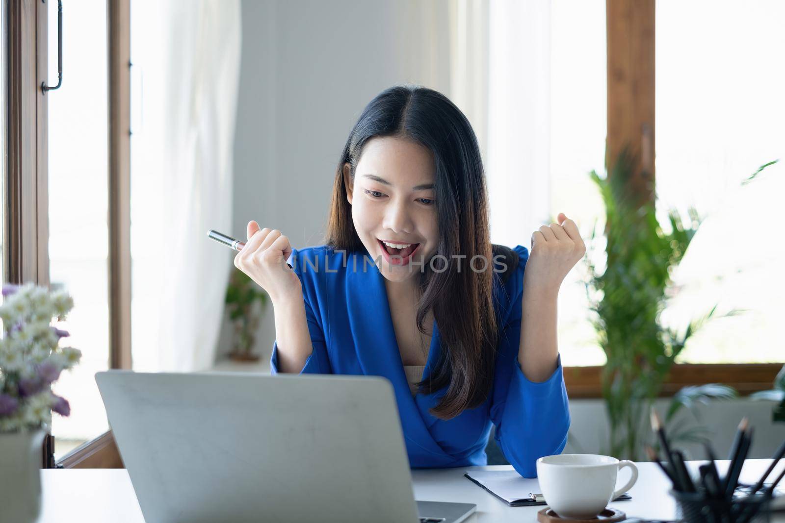 Asian Woman blogger wear blue suit talking with followers, live streaming on social media application. Freelance work from home concept