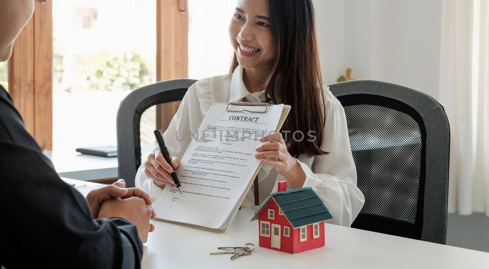 Real estate brokers point to a contract paper and advise customers to sign their names. customer sign agreement contract signature for buy or sell house. Real estate concept contact agreement concept.