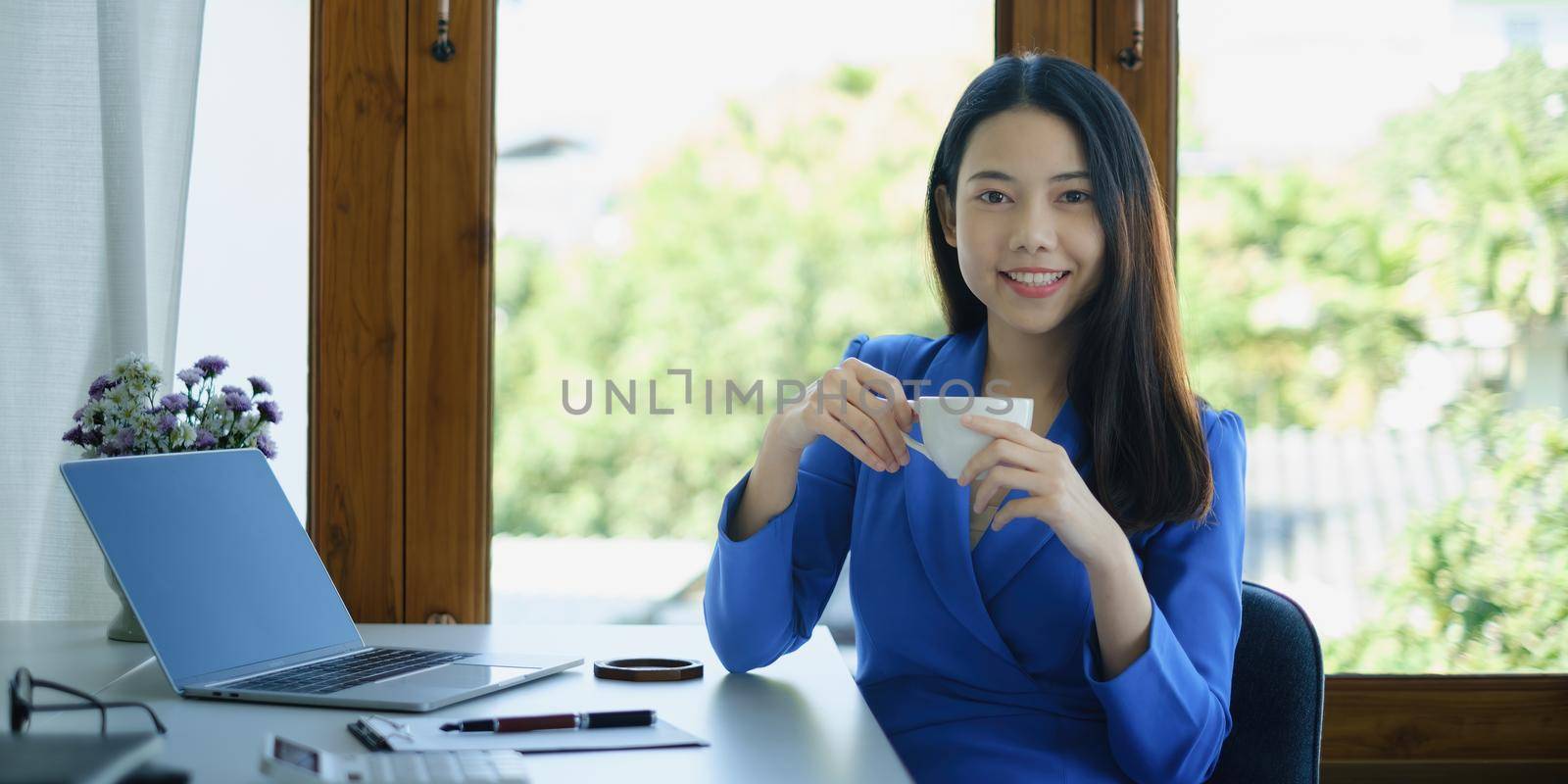 Asian Woman blogger wear blue suit talking with followers, live streaming on social media application. Freelance work from home concept. by itchaznong
