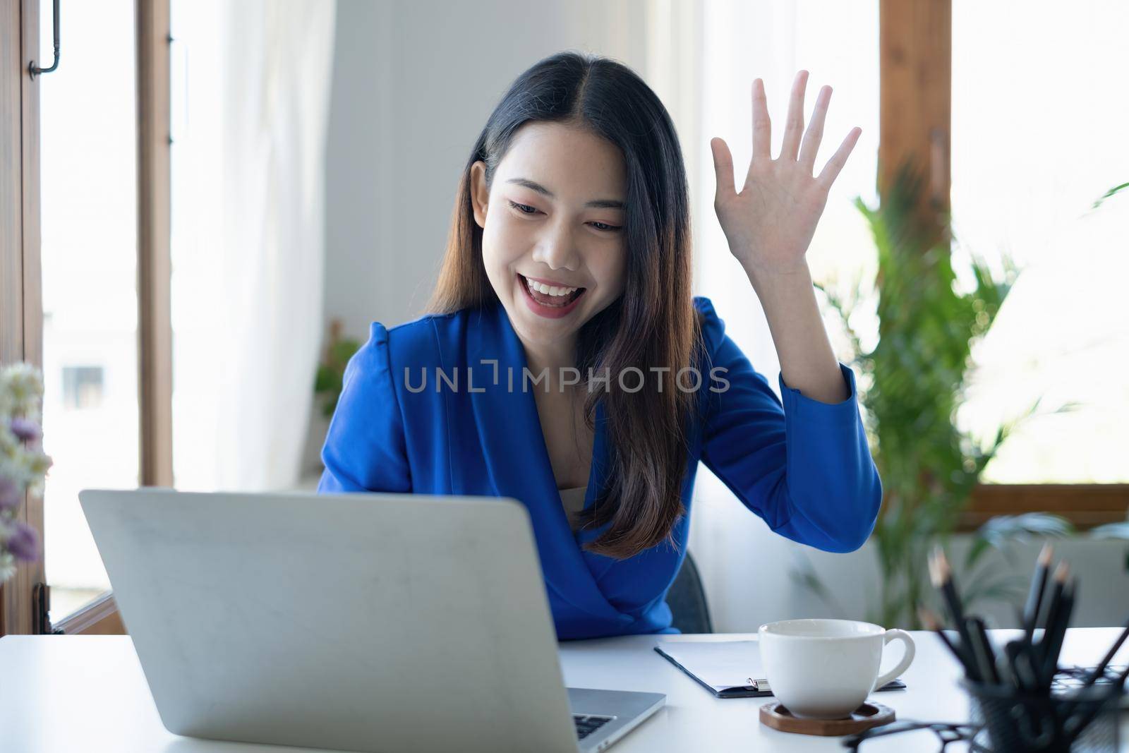 Asian Woman blogger wear blue suit talking with followers, live streaming on social media application. Freelance work from home concept