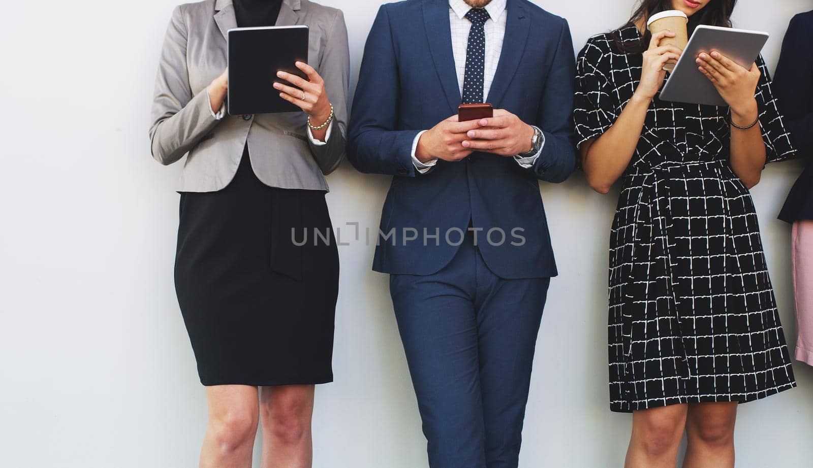 Cropped shot of three unrecognizable businesspeople using technology while standing in the office during the day