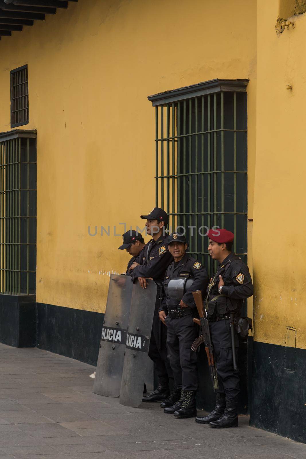 Lima, Peru - September 02, 2015: Four policemen guarding a side road to the central square in front of the government palace on a Wednesday afternoon.