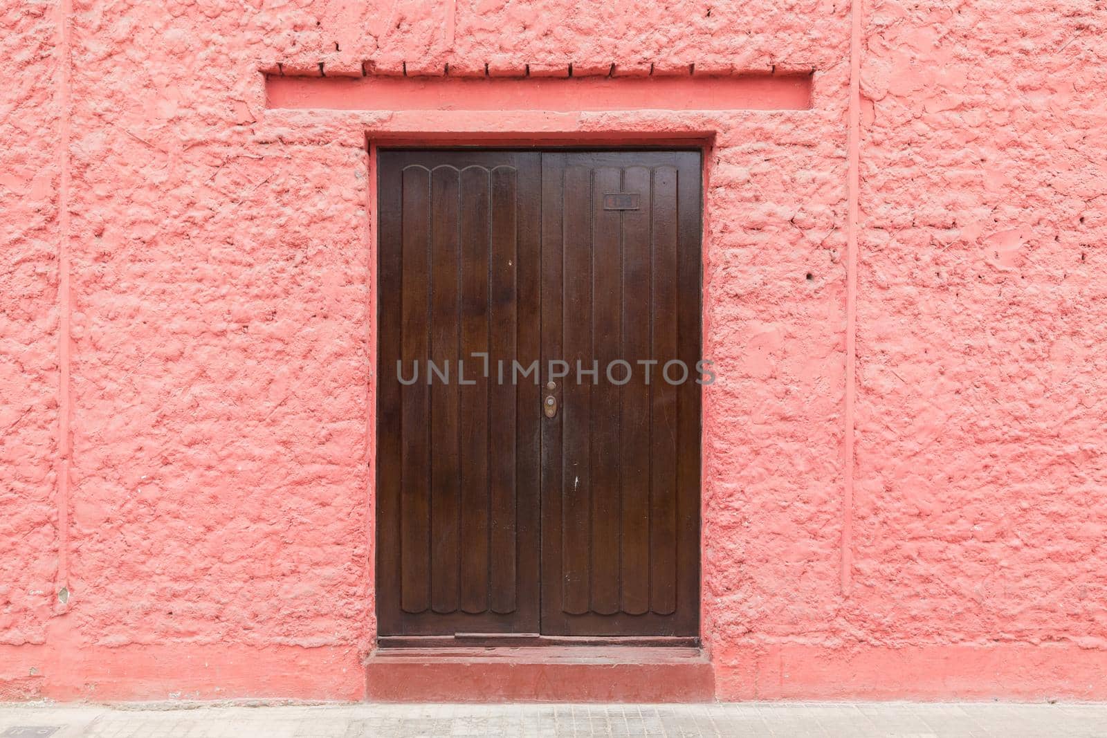 Lima, Peru - September 03, 2015: Photograph of a pink wall with a wooden door.