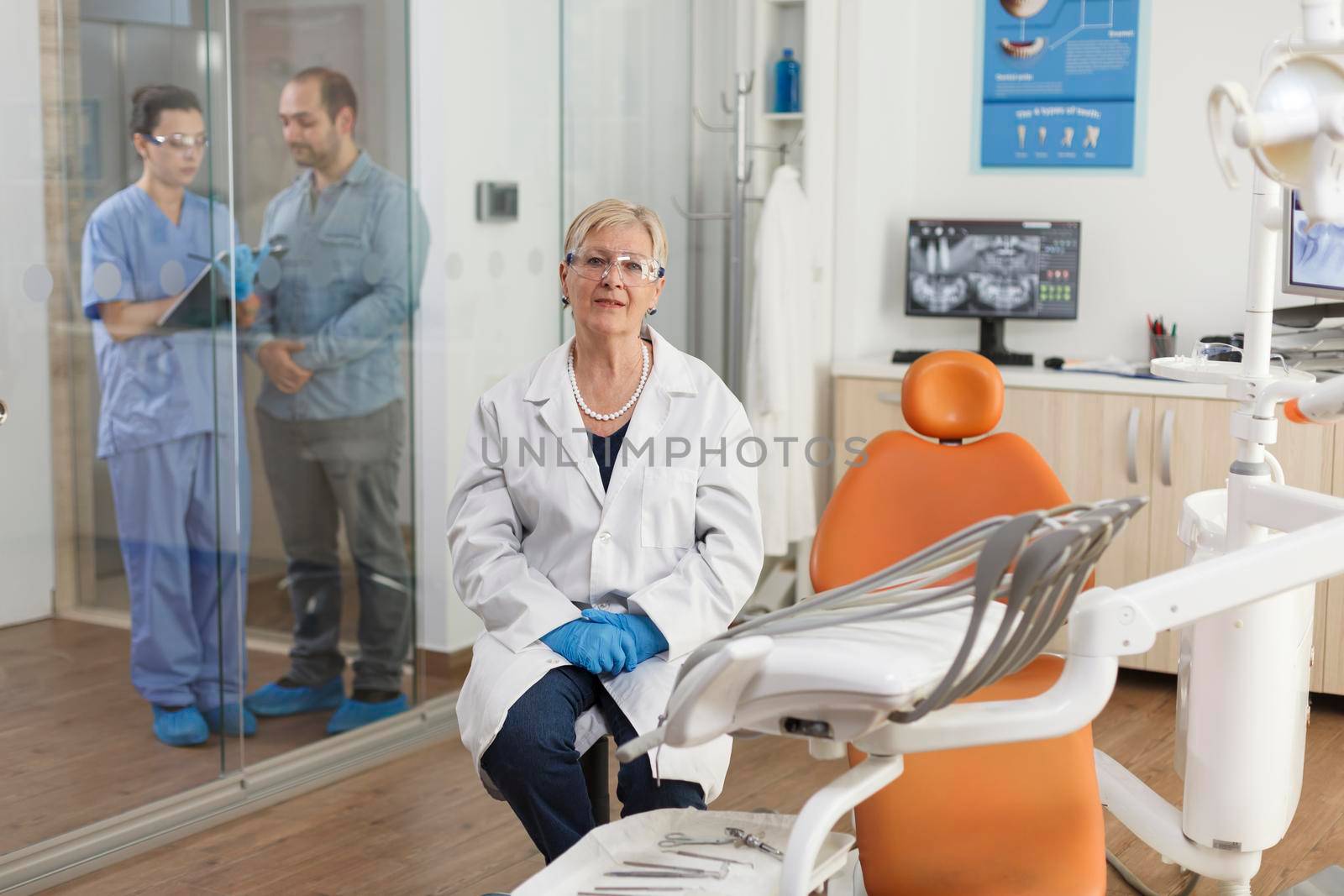 Portrait of stomatologist doctor looking into camera while waiting for patient during stomatology consultation in medical dental office. Orthodontist senior woman working at dentistry treatment