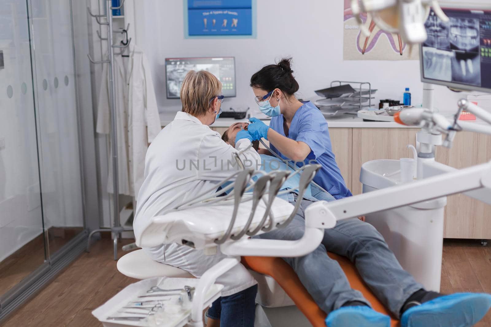 Orthodontist team with medical face masks working at patient teeth by DCStudio