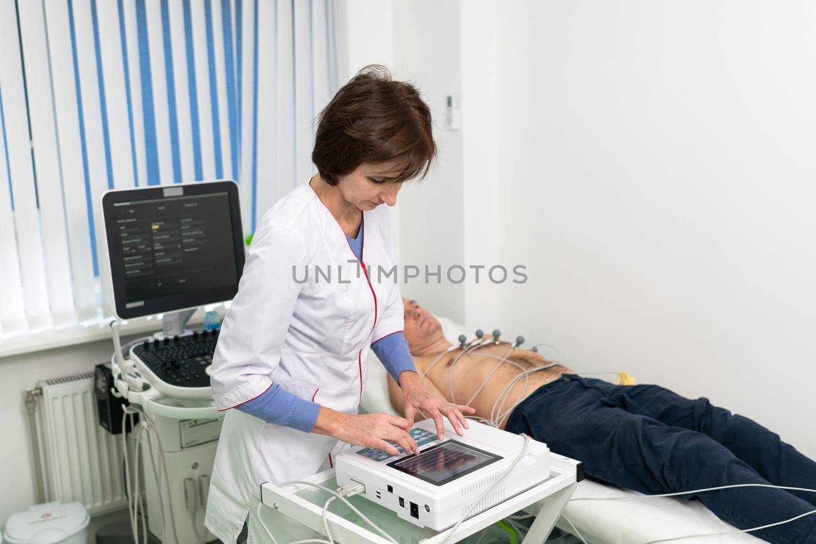ECG concept. Woman doctor cardiologist doing electrocardiogram test to man patient in cardiology clinic. Medicine, cardiology, ECG of the heart concept. Male at medical testing.