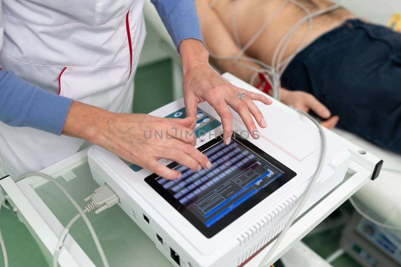 ECG concept. Woman doctor cardiologist doing electrocardiogram test to man patient in cardiology clinic. Medicine, cardiology, ECG of the heart concept. Male at medical testing by Tomashevska