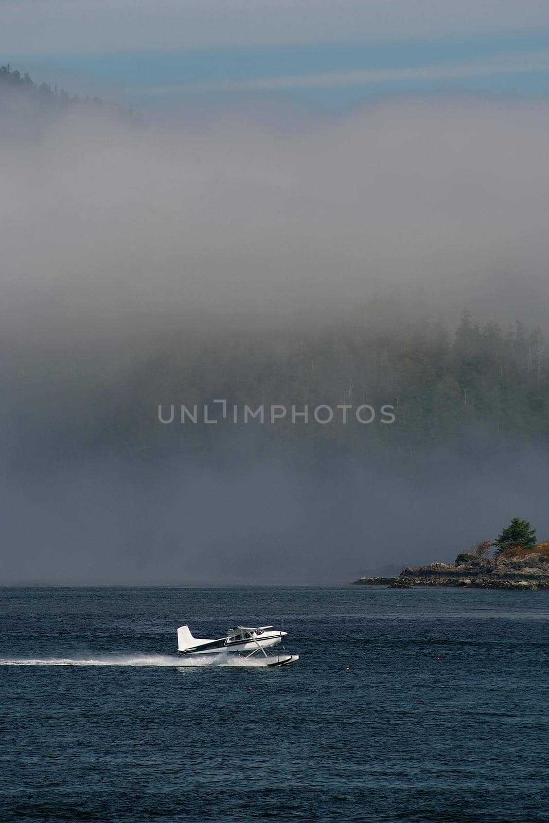 A Float Plane Accelerates for Takeoff in Tofino on Vancouver Island in Canada surrounded by low hanging clouds. High quality photo