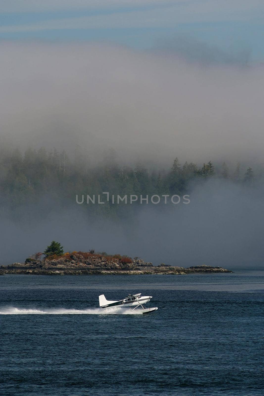 A Float Plane Accelerates for Takeoff in Tofino on Vancouver Island in Canada surrounded by low hanging clouds. High quality photo