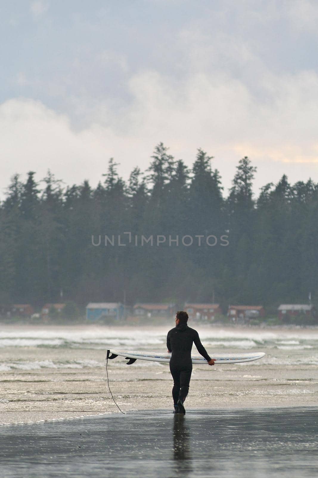 A Surfer Carries his Board Along the Beach in Tofino British Columbia in Canada by markvandam