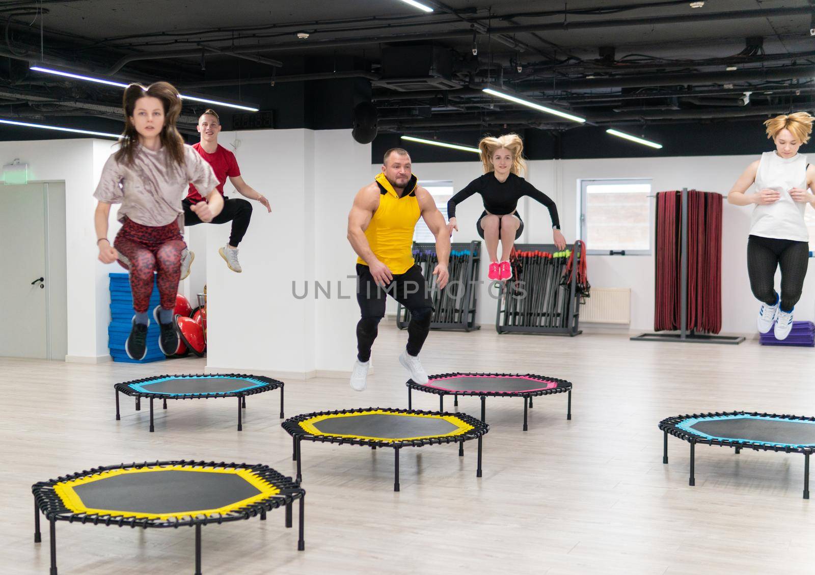 Women's and men's group on a sports trampoline, fitness training, healthy life - a concept trampoline group batut instructor health, for lifestyle athletic for sporty and young person, smiling sportswear. Studio happy athlete, coach by 89167702191