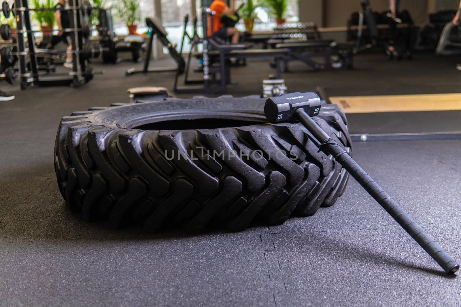A tire on a black background with a sledgehammer lies for crosfit fitness wheel sledgehammer workout black weight, In the afternoon training exercise for adult health push, big build. Young huge diet, flipping