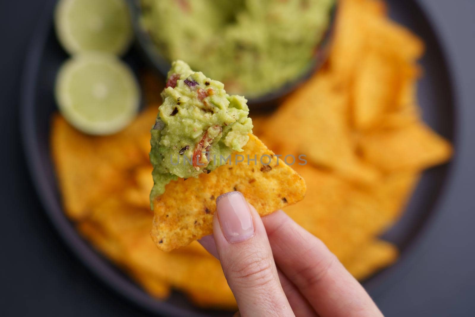 Closeup of woman hand holding guacamole and chips or nachos. Top view. High quality photo