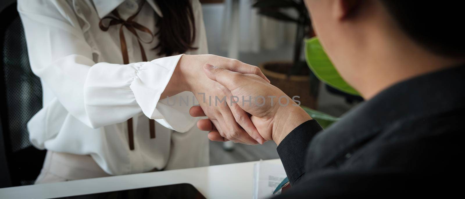 Business people handshake for teamwork of business merger and acquisition, successful negotiate, two asian business people shake hand with partner to celebration partnership and business deal concept. by nateemee