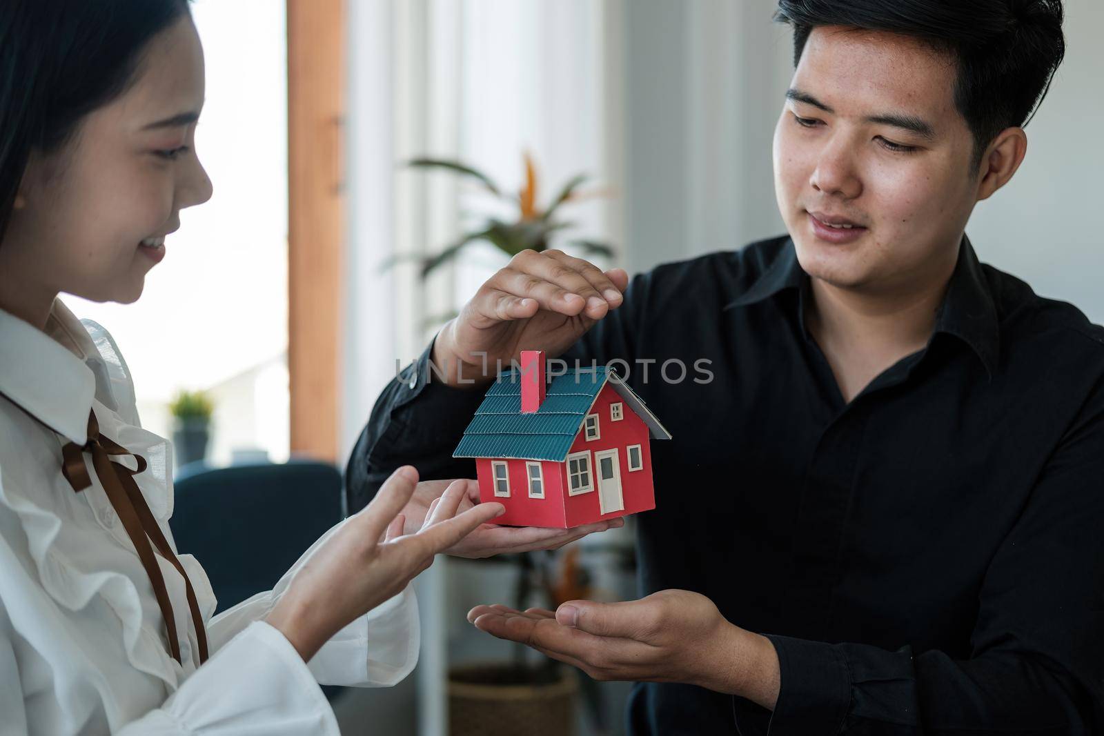Asian couple are using their hands to protect The concept of the use of gestures in real estate investors, leasing insurance, purchase and sales contracts and maintenance.