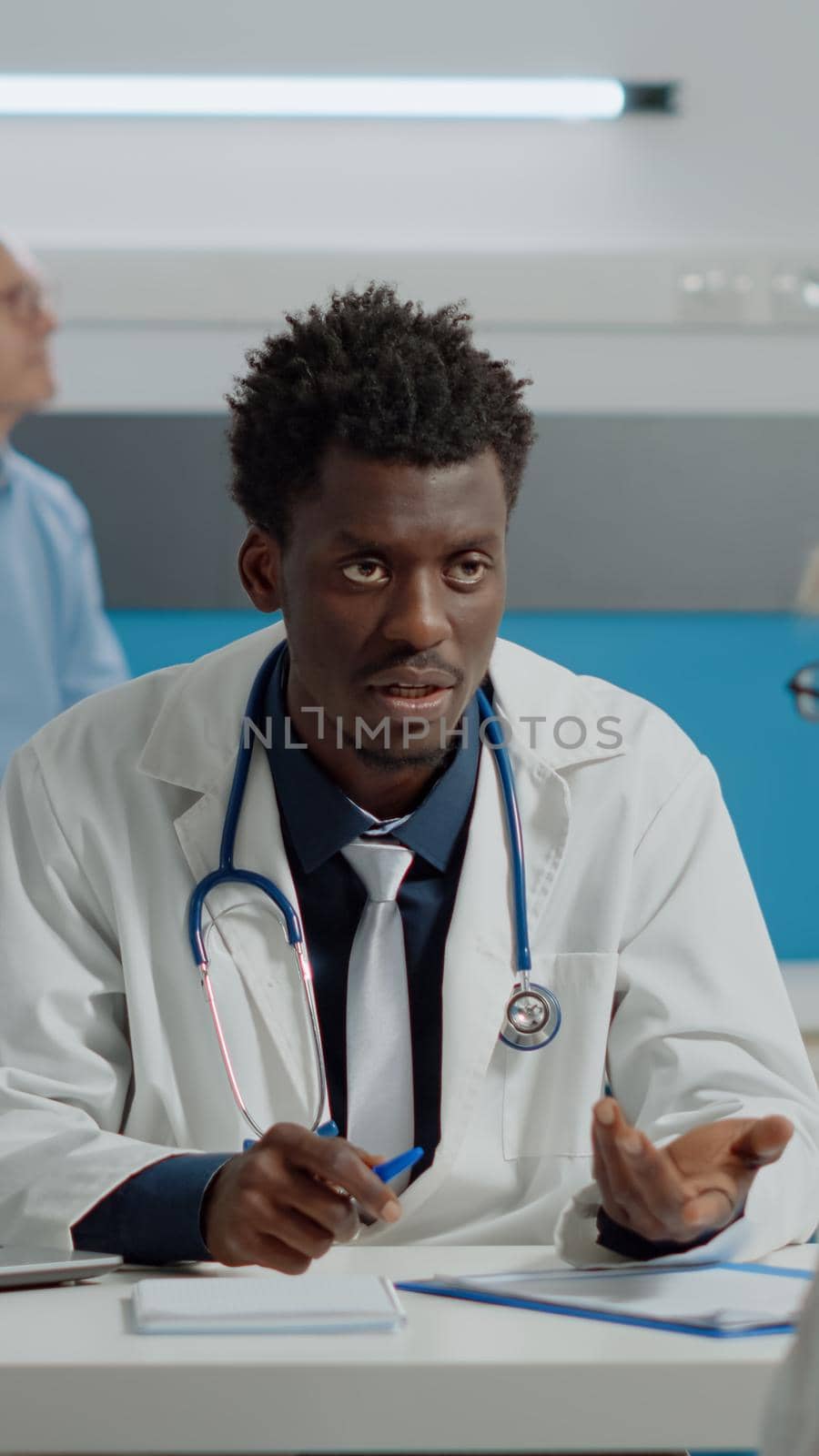 Doctor consulting old patient and having green screen on laptop in medical cabinet. Display of chroma key template with isolated mockup background on desk while medic discussing with elder woman