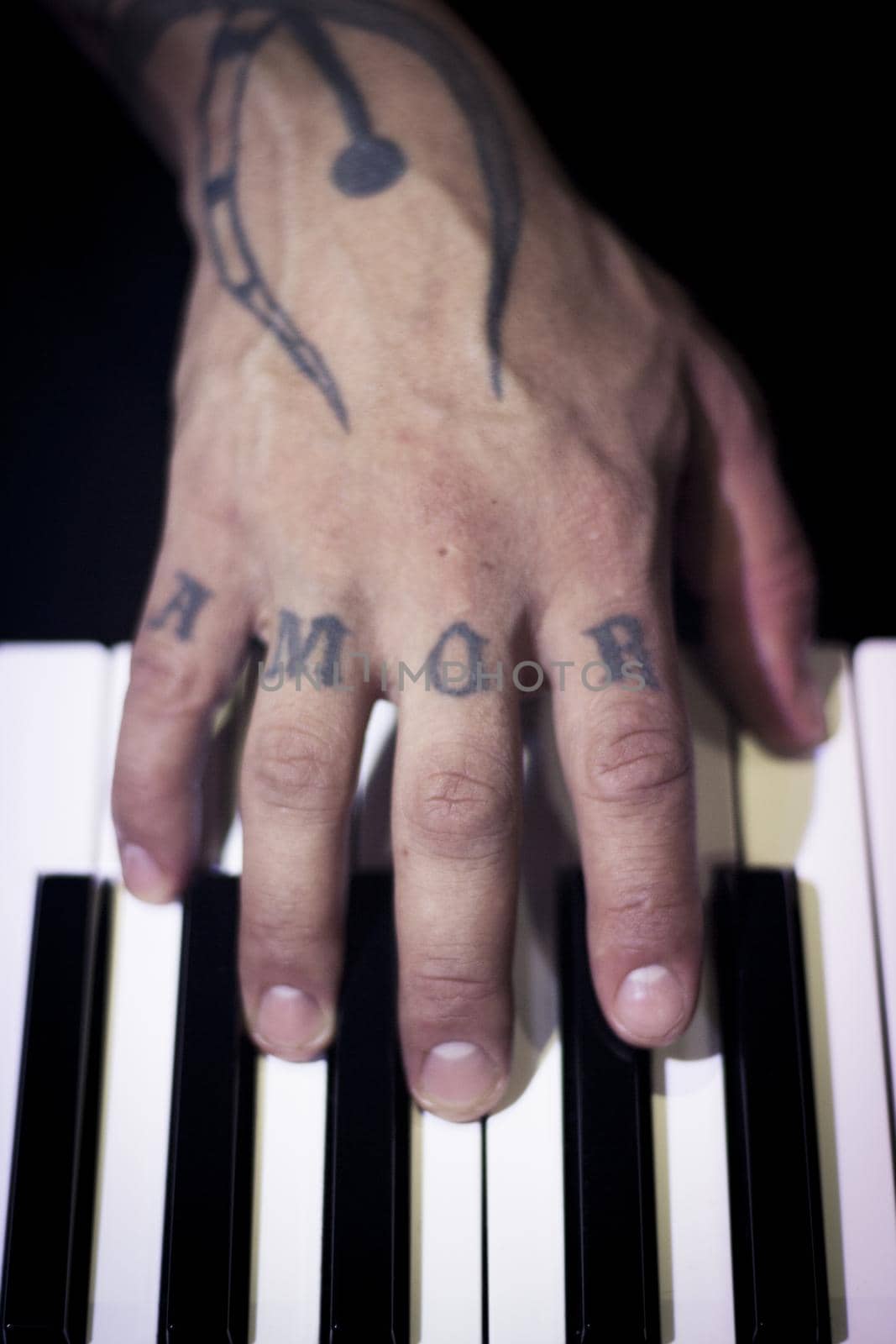 Tattooed mans hands on the keyboard of a piano by GemaIbarra