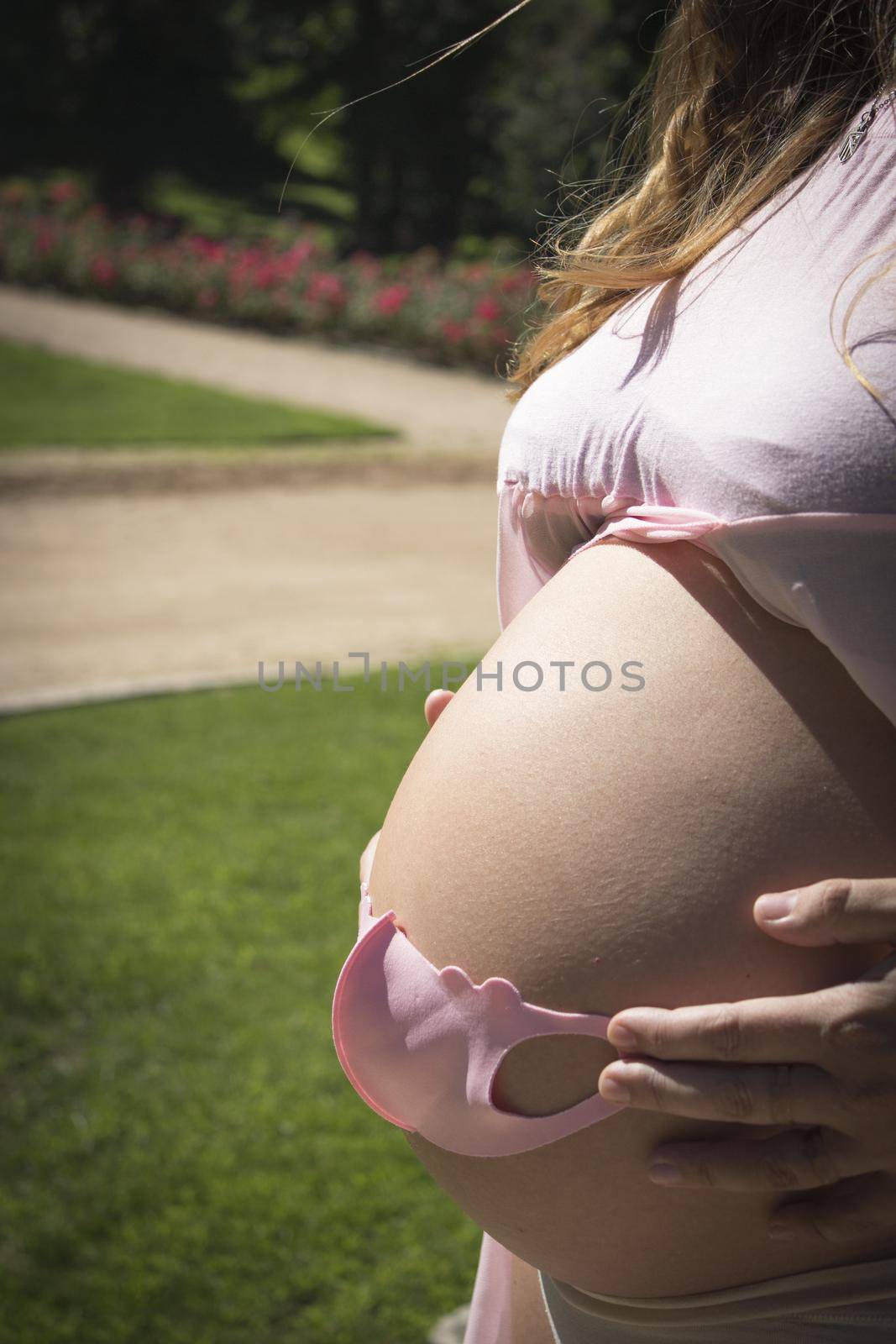 Seven months pregnant woman with baby mask over her gut. Pink color