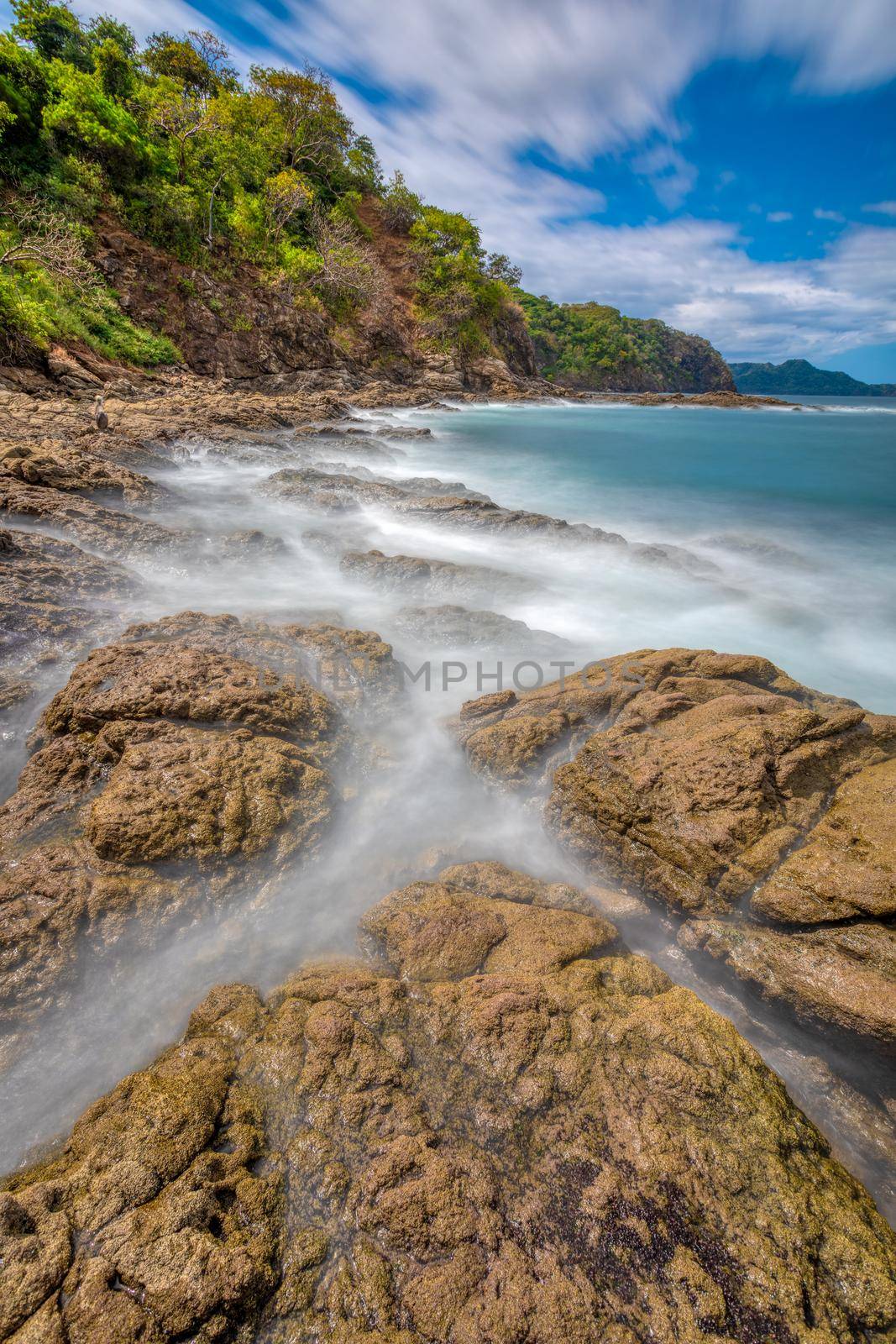 Long exposure, pacific ocean waves on rock in Playa Ocotal, El Coco Costa Rica. Famous snorkel beach. Picturesque paradise tropical landscape. Pura Vida concept, travel to exotic tropical country.
