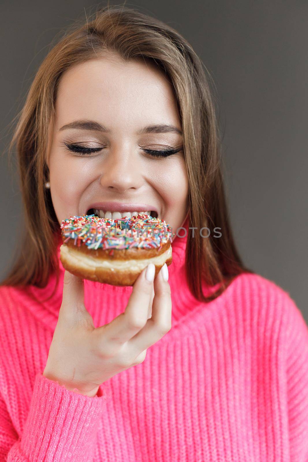 Young happy woman with donut smiling by splash