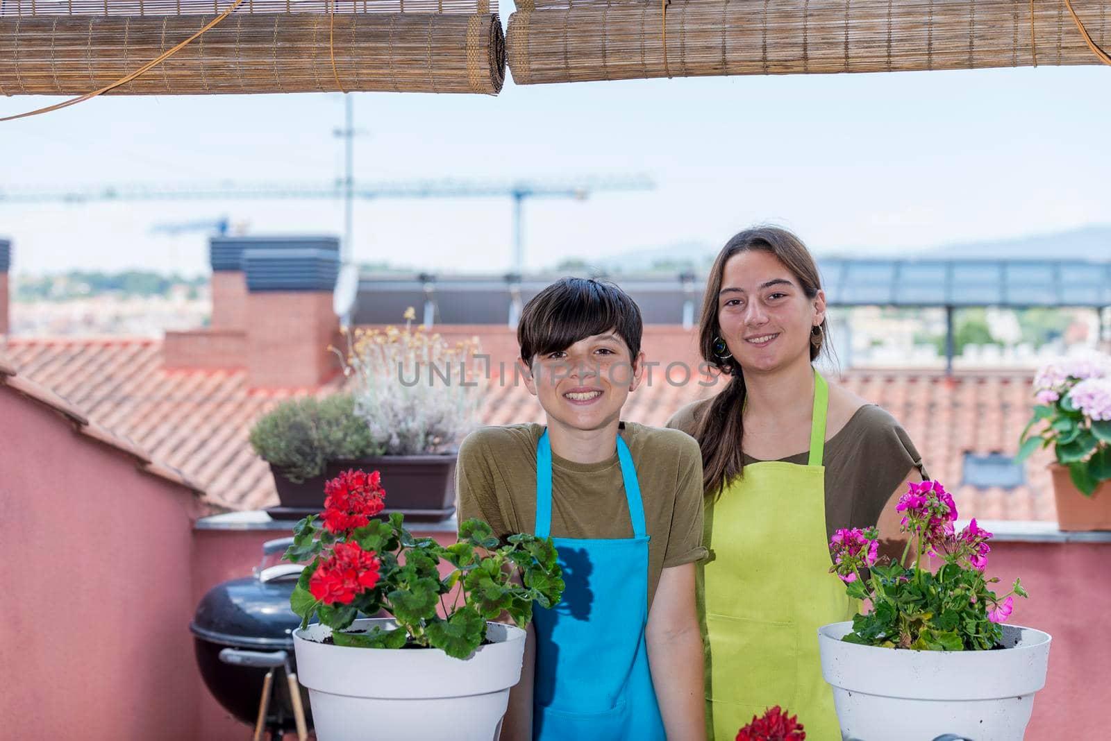 Two teenage holding plant pots while smiling on the terrace