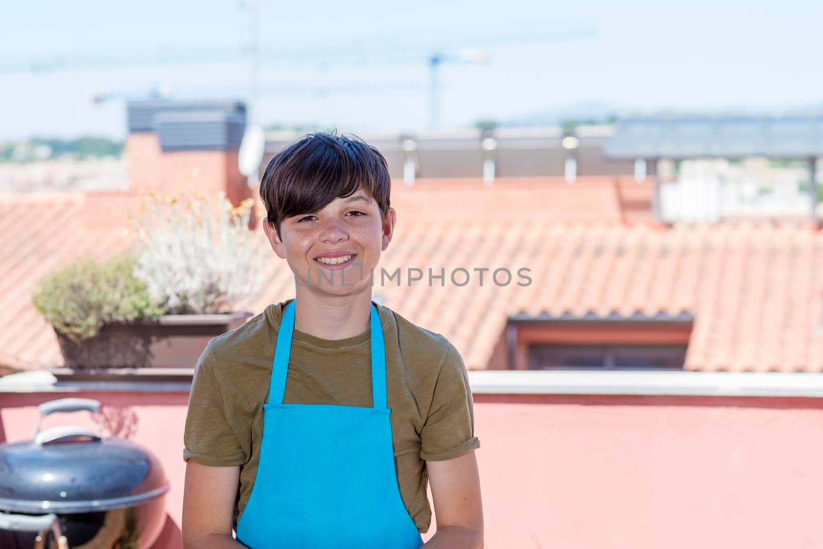 Young happy teen standing at terrace wearing a gardener apron