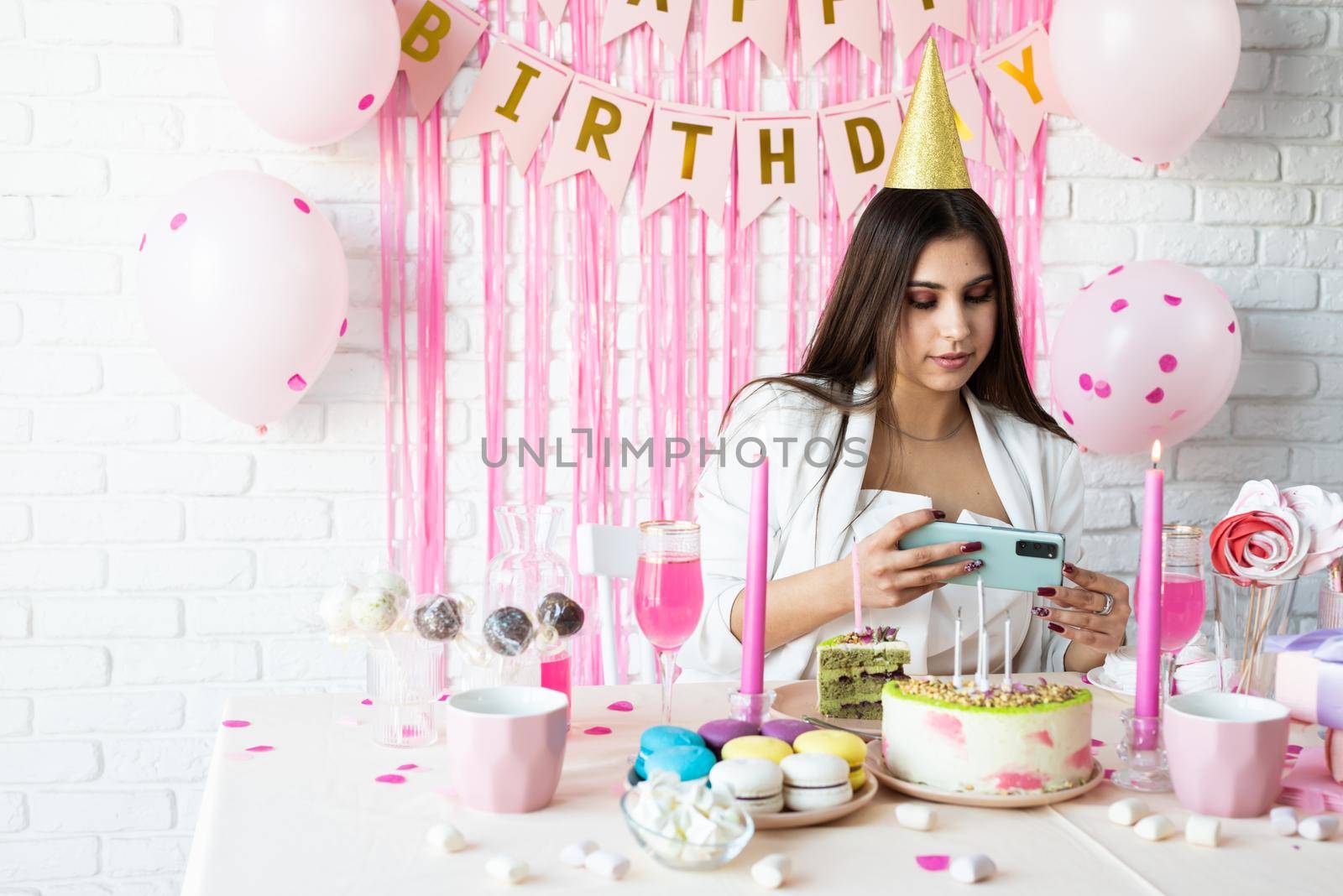 Birthday party. Birthday tables. Attractive woman in white party clothes celebrating birthday taking selfie on mobile