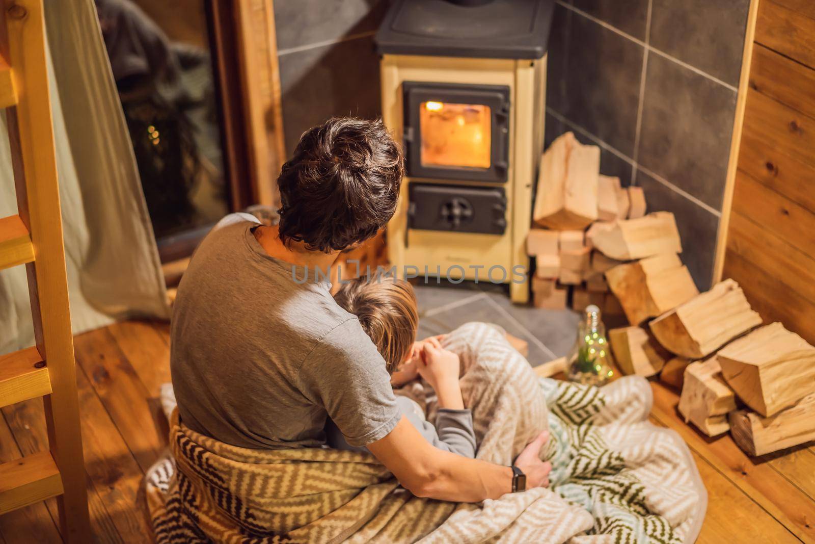 Dad and son spend time by the fireplace in Glamping. Rest in the mountains in Glamping. Cozy fireplace in a mountain house by galitskaya