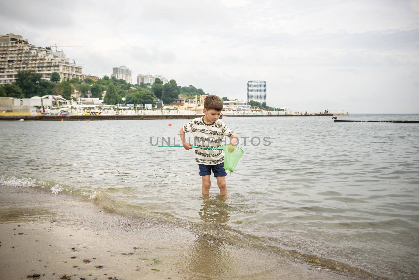 One little boy alone exploring the beach at low tide walking towards the sea coast. happy childhood concept.
