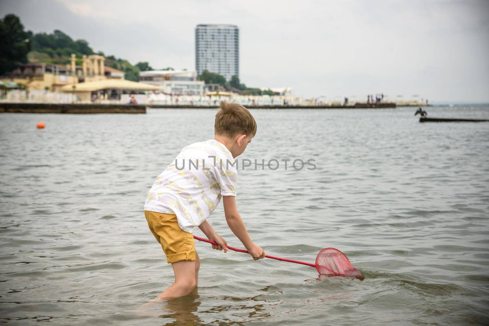 One little boy alone exploring the beach at low tide walking towards the sea coast. happy childhood concept.