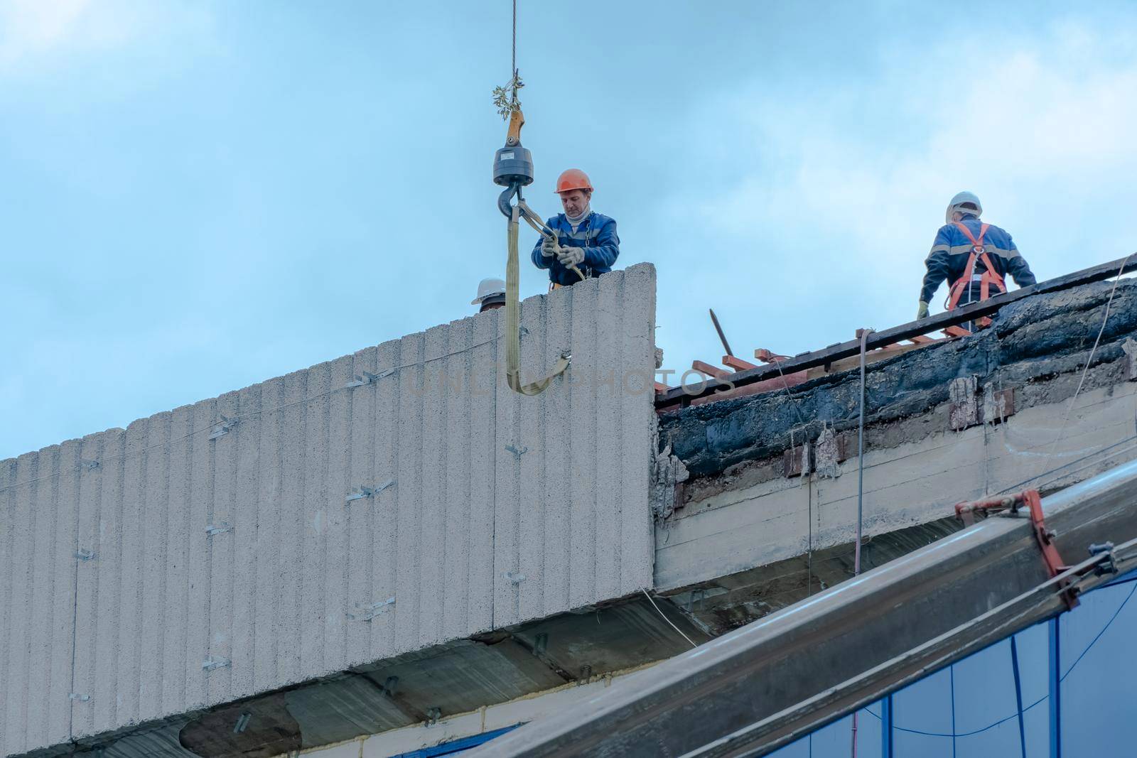 Moscow,Russia,05,10,2021:Restoration,reconstruction and repair of the building.Construction workers in hard hats install concrete slabs on the roof of the structure.Housing Restoration Construction by YevgeniySam