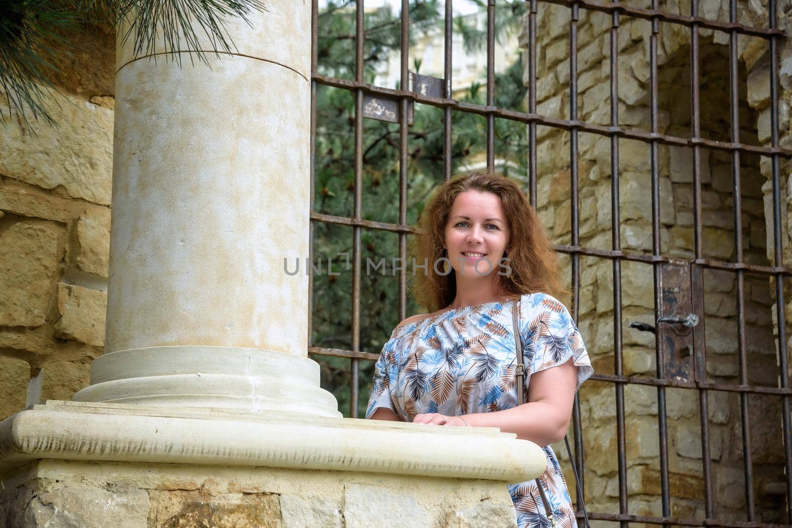 Portrait of young pretty woman on stairs near ancient historical building from stone and seashells.