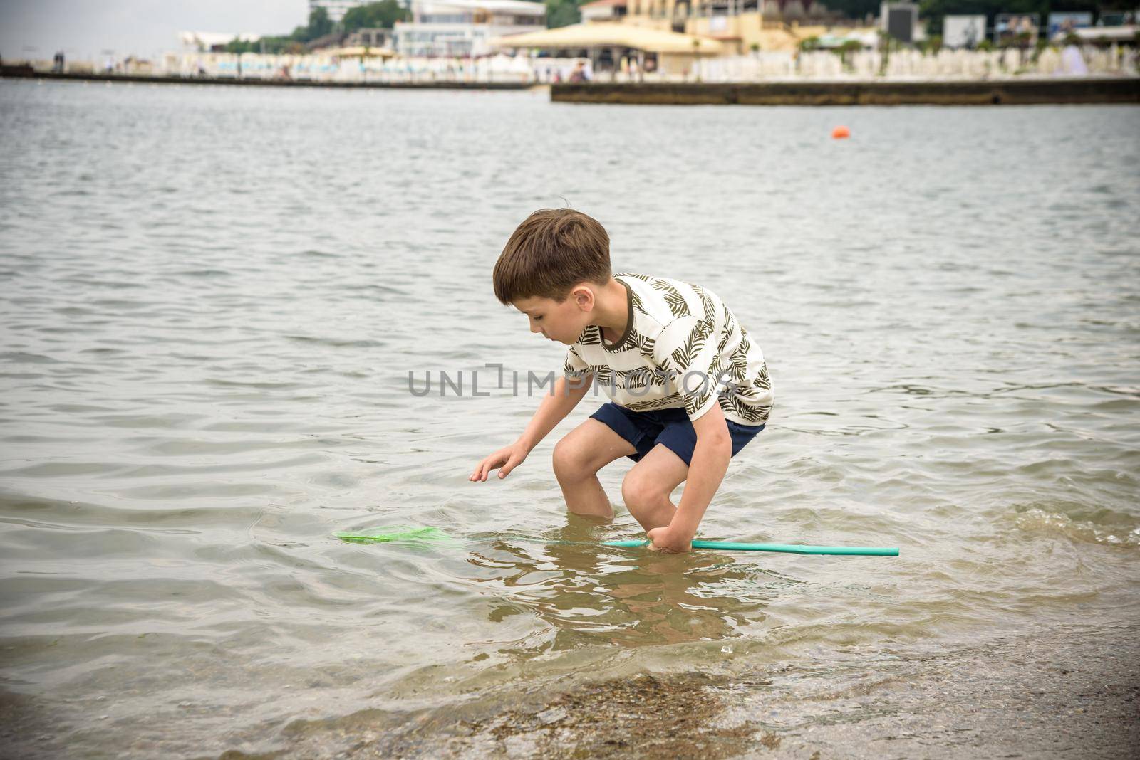 One little boy alone exploring the beach at low tide walking towards the sea coast. happy childhood concept.