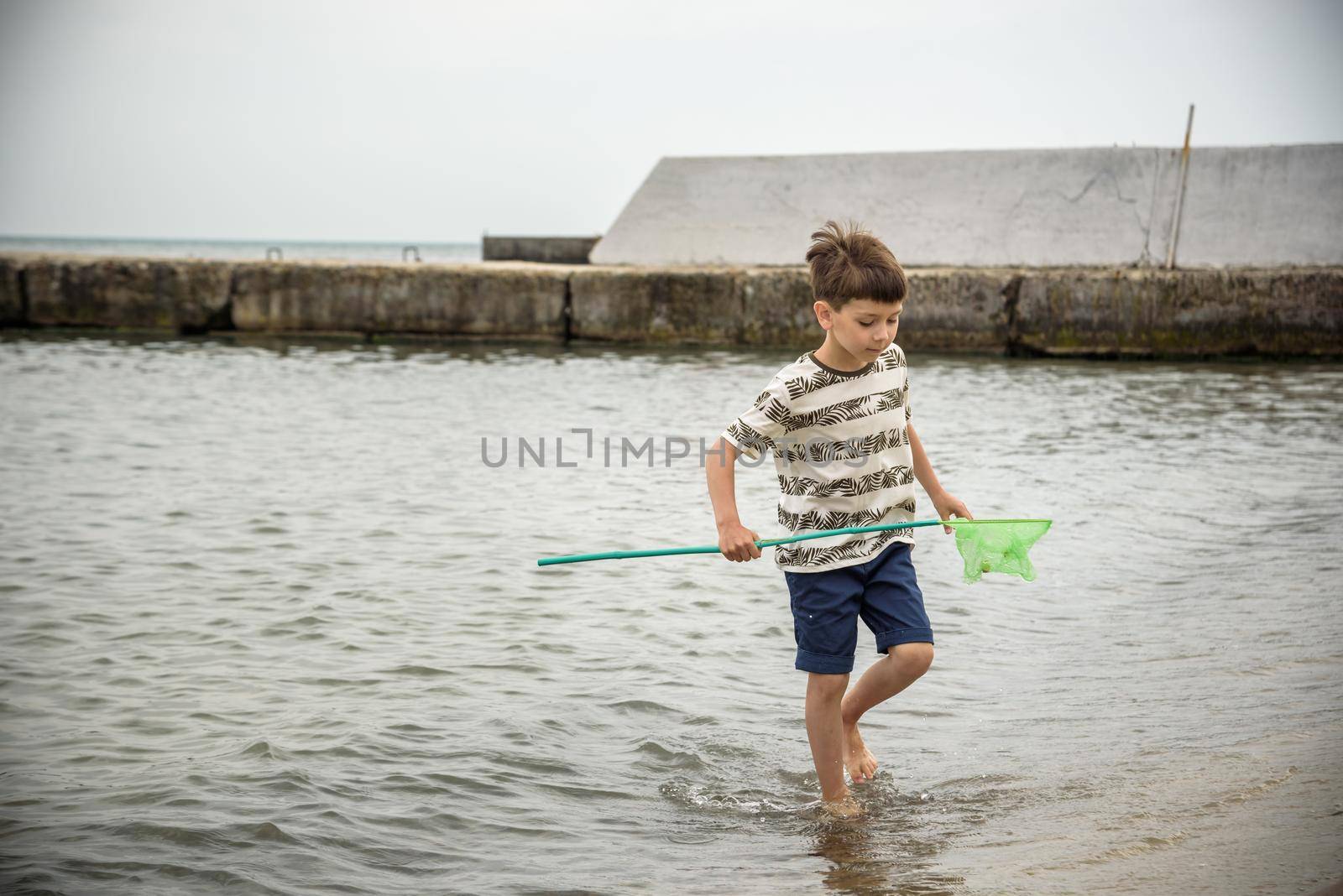 One little boy alone exploring the beach at low tide walking towards the sea coast. happy childhood concept.