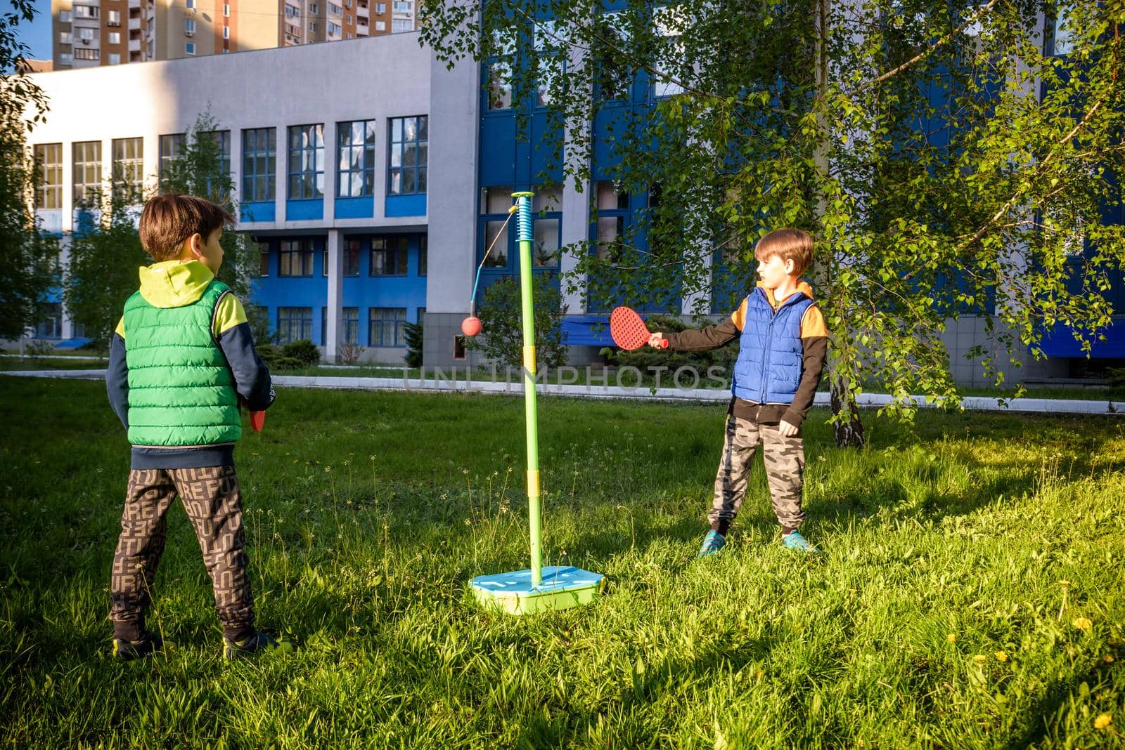 Two friends are playing tetherball swing ball game in summer camping. Two boy brother happy leisure healthy active time outdoors concept.