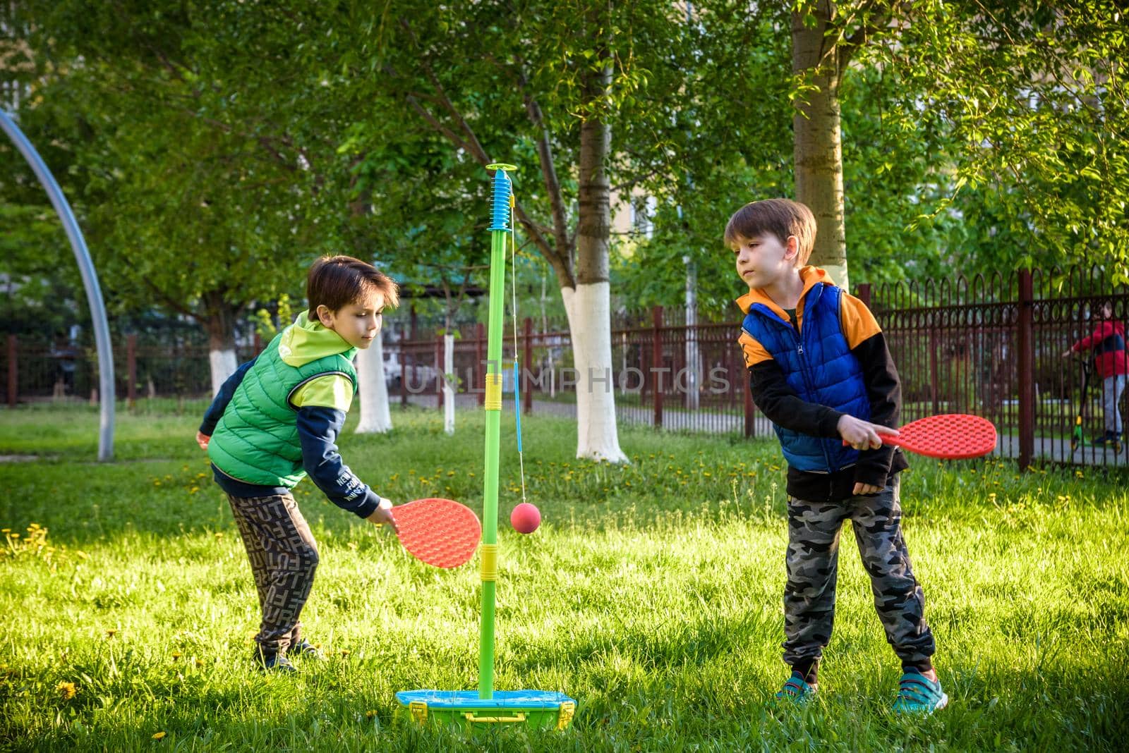 Two friends are playing tetherball swing ball game in summer camping. Two boy brother happy leisure healthy active time outdoors concept.