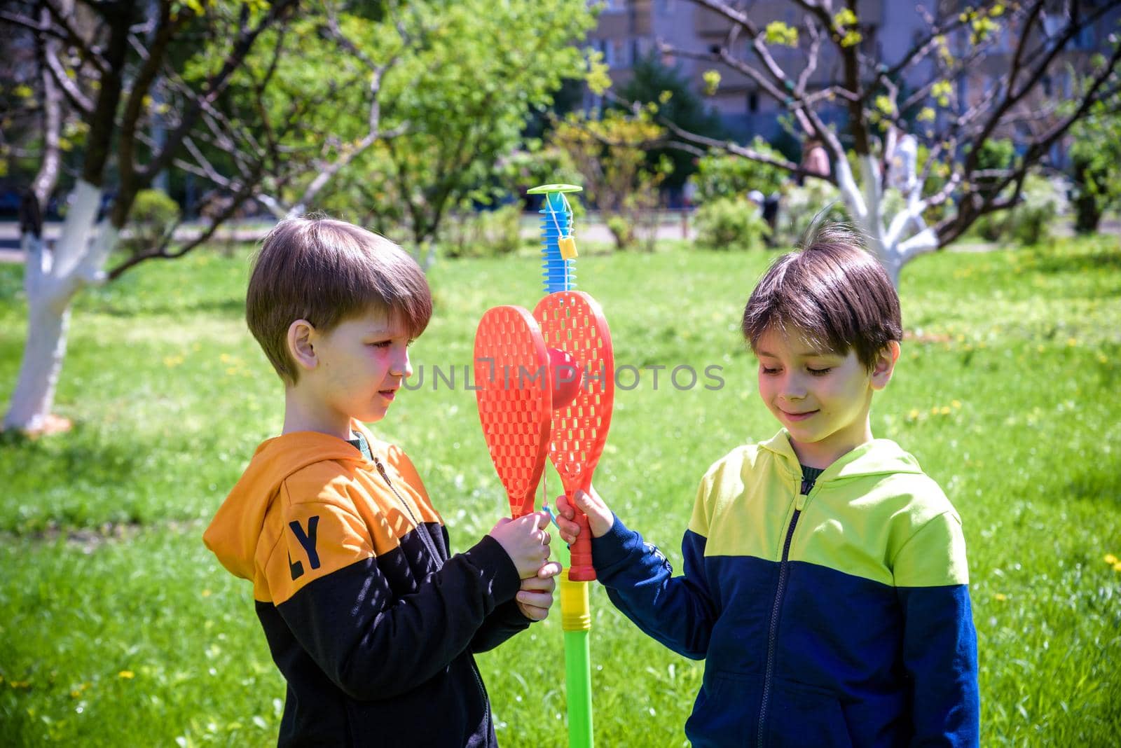 Two friends are playing tetherball swing ball game in summer camping. Two boy brother happy leisure healthy active time outdoors concept by Kobysh