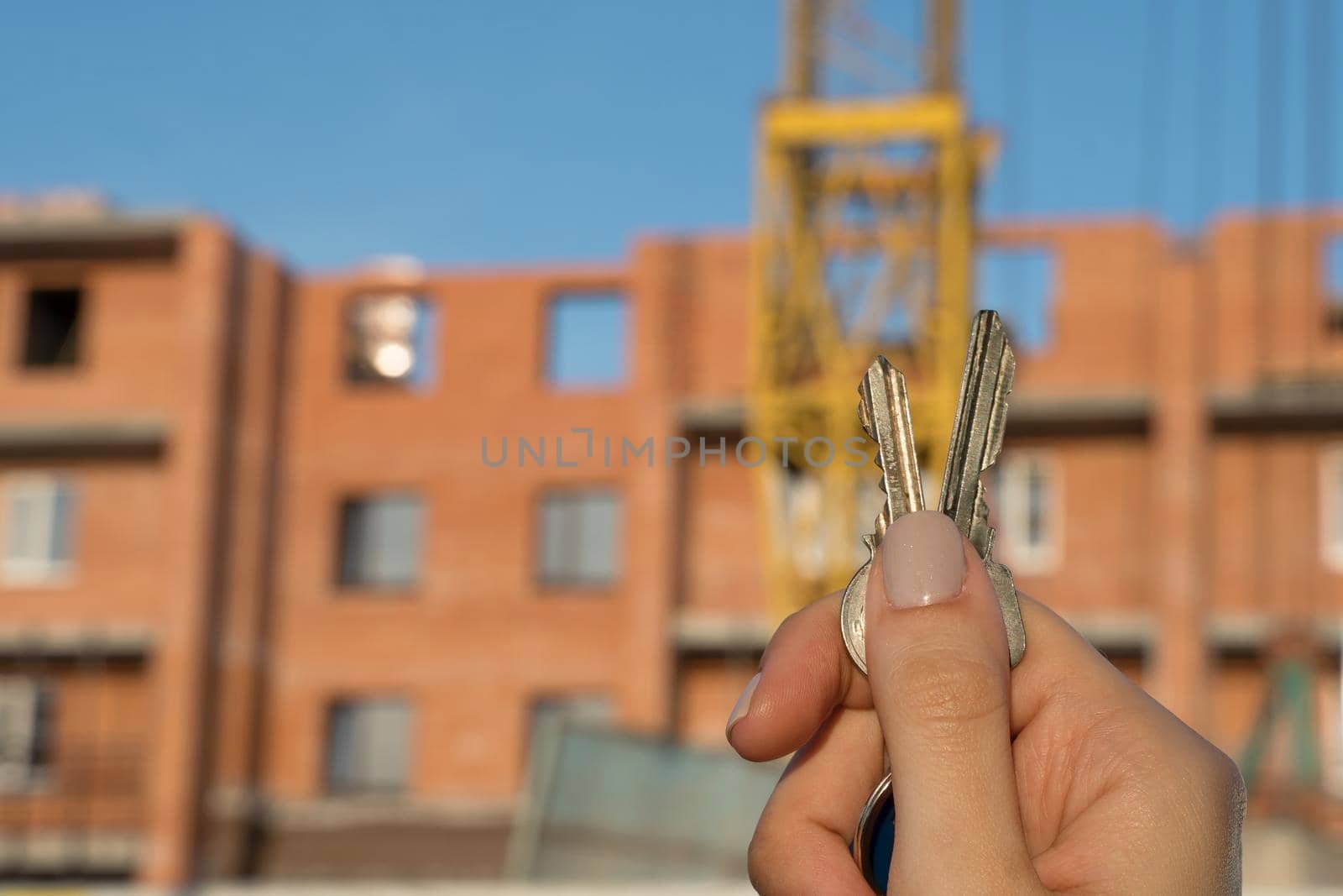 Construction of a new building or a new skyscraper.Construction site.Hands holding the keys to a new home.Mortgage for the construction of apartments.Buy real estate and property.Debt obligations by YevgeniySam