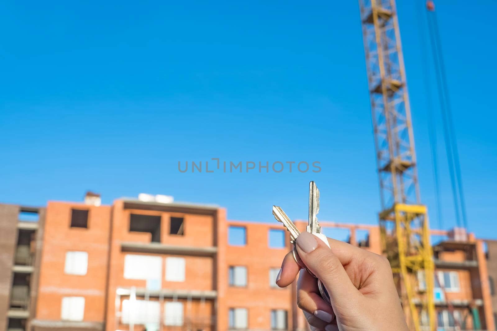 Construction of a new building or a new skyscraper.Construction site.Hands holding the keys to a new home.Mortgage for the construction of apartments.Buy real estate and property.Debt obligations by YevgeniySam