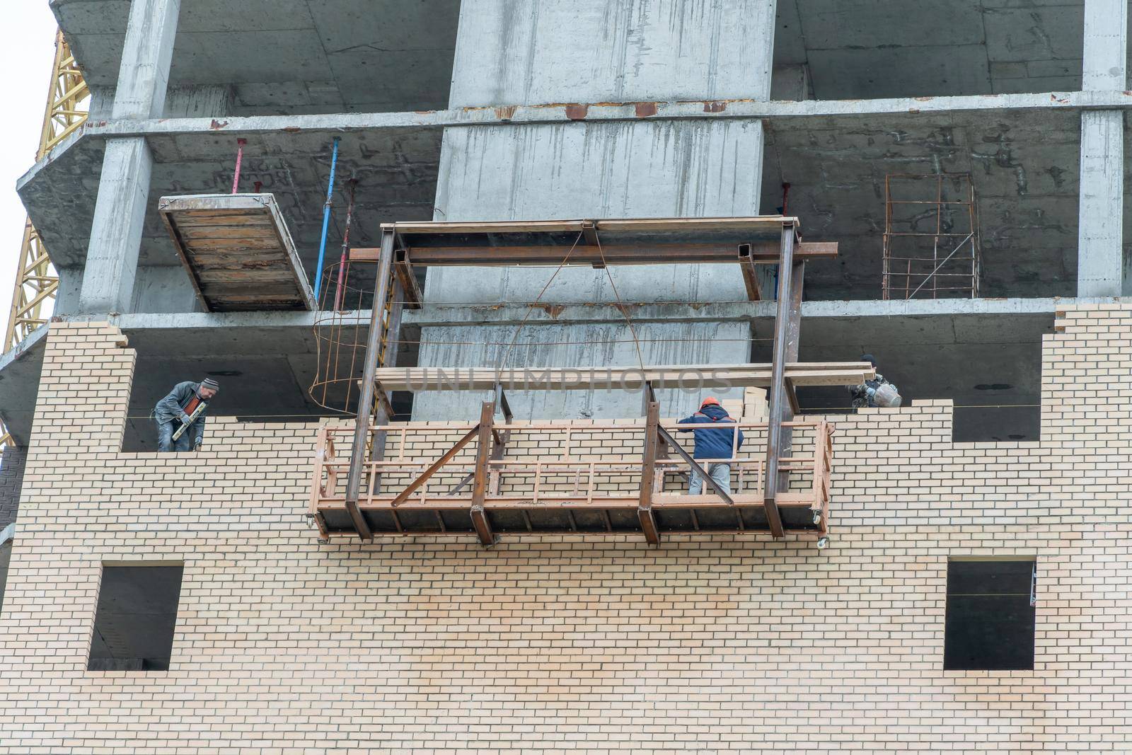 Moscow,Russia,05,10,2021:Restoration, reconstruction and repair of the building.Construction workers are standing on a lifting platform and laying bricks.Housing Restoration Construction Site