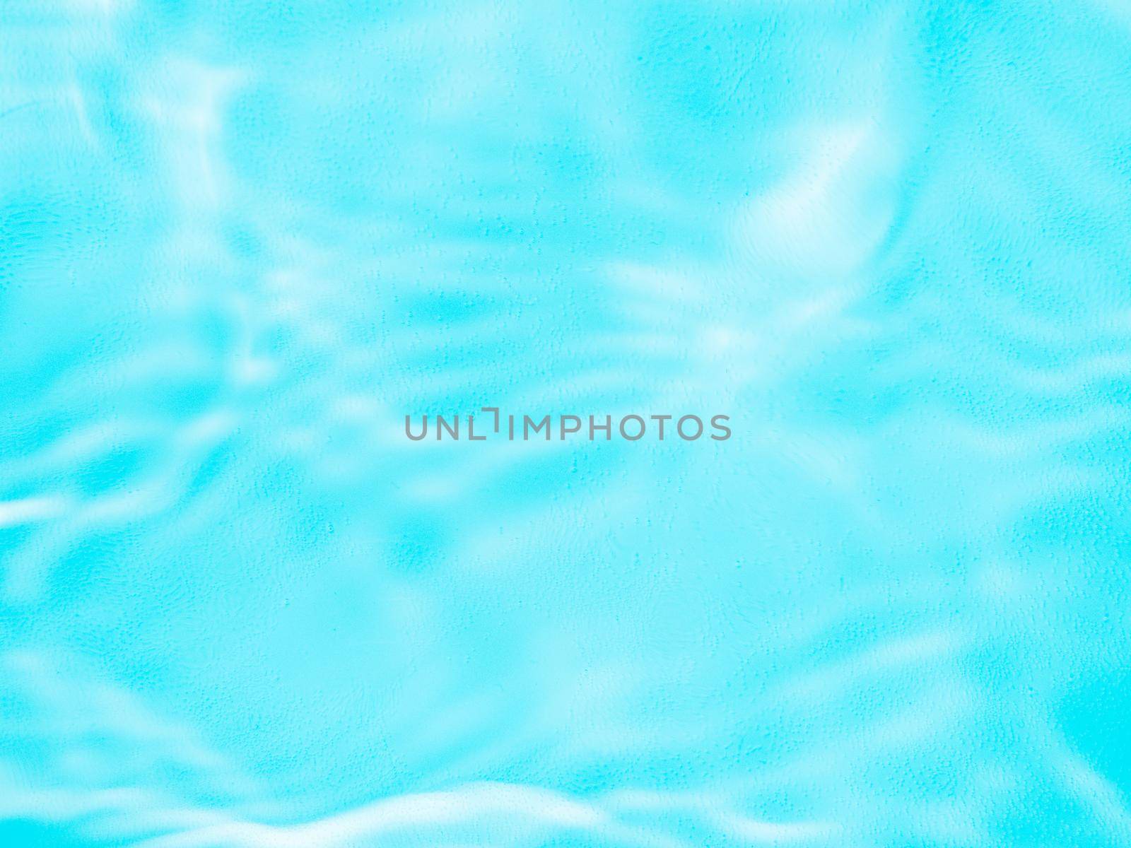 Ripple water texture on blue pool background. Shadow of water on sunlight. Mockup for product, spa or travel background. Marble blue water surface as wallpaper background