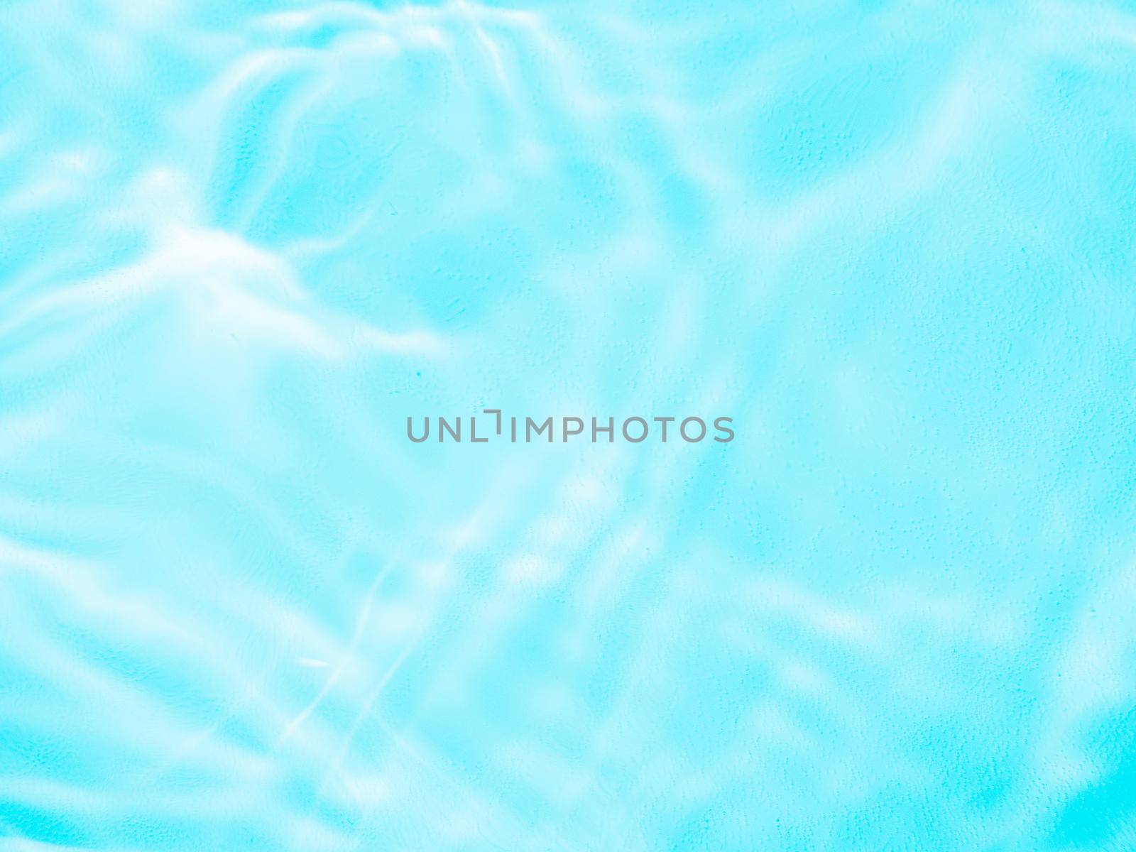 Ripple water texture on blue pool background. Shadow of water on sunlight. Mockup for product, spa or travel background. Marble blue water surface as wallpaper background