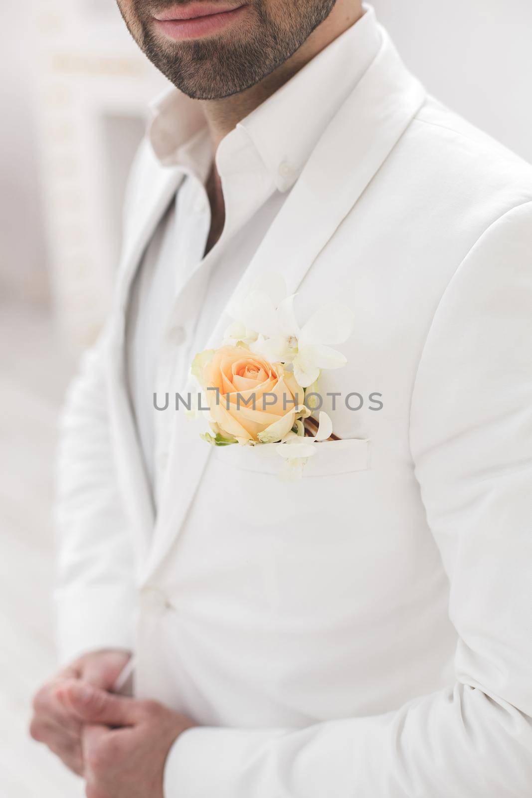 Elegant young handsome man with a beard in a white classic suit.