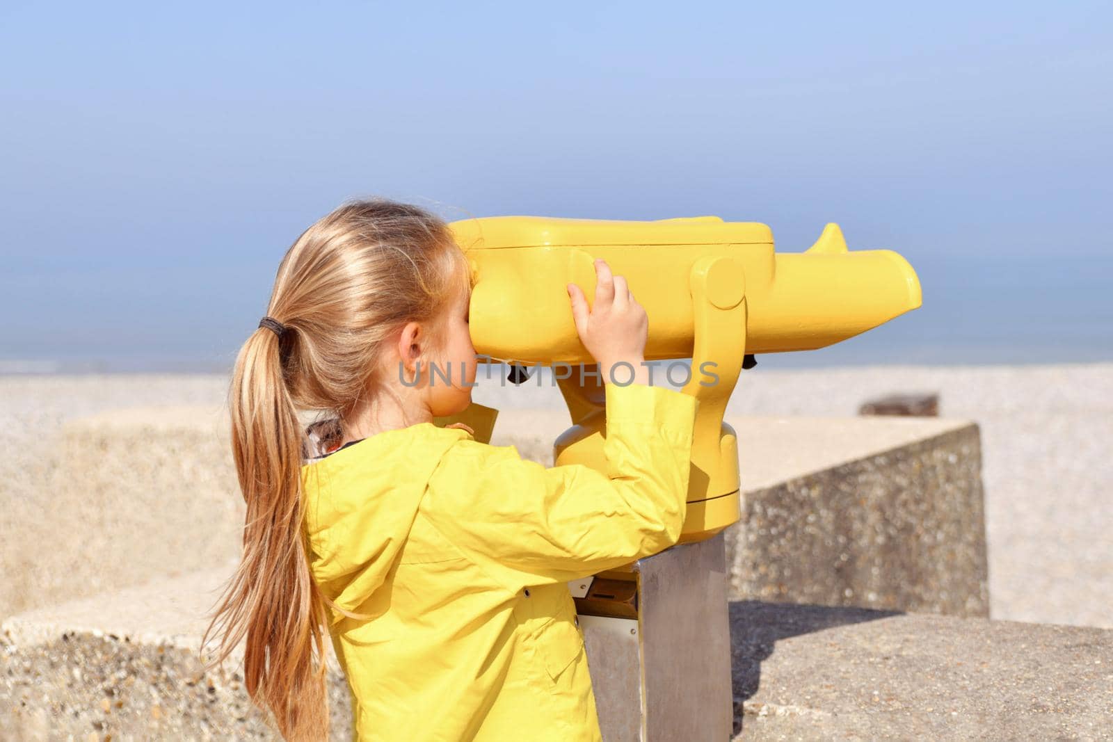Girl looking at the ocean through a binoscope