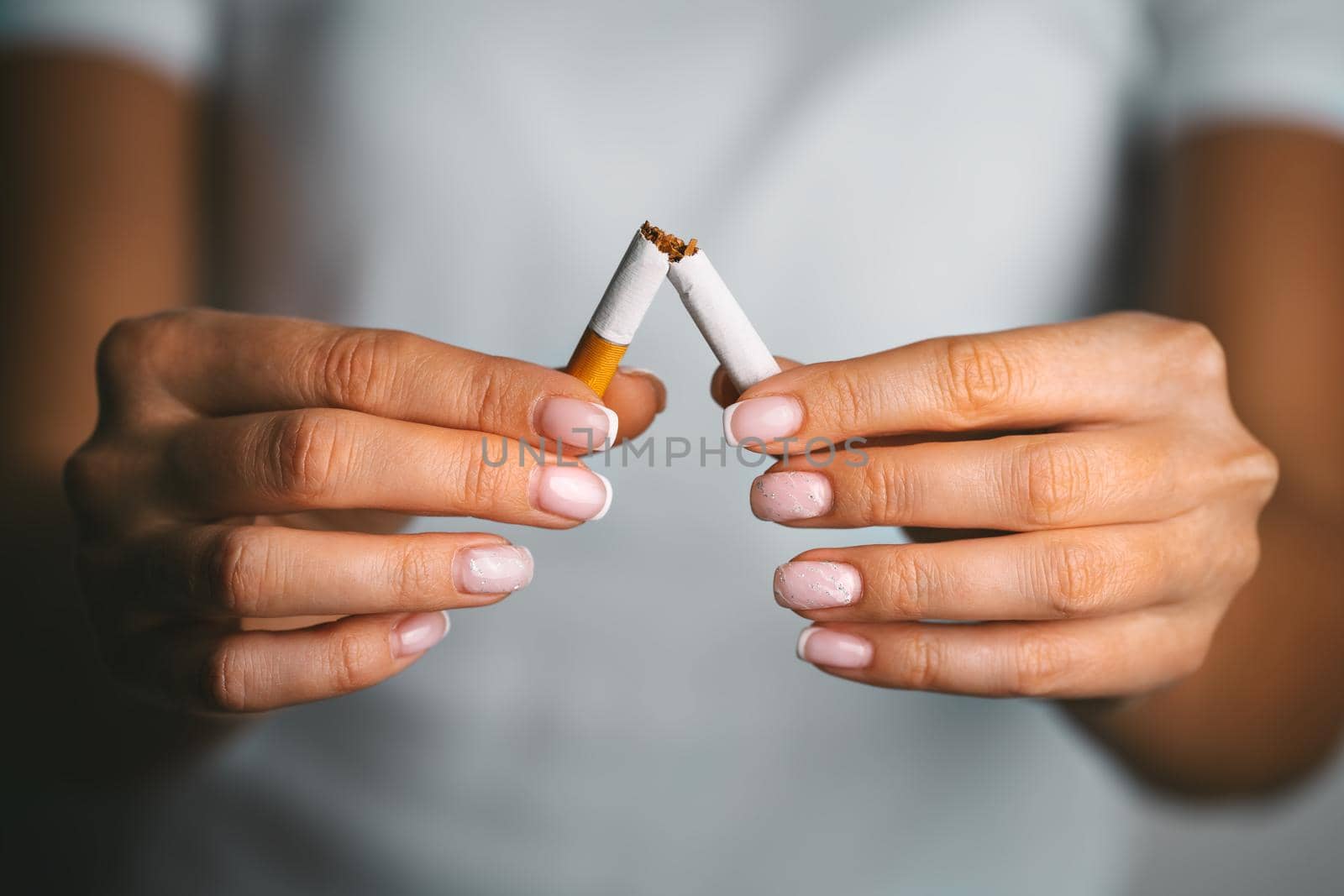 Stop smoking, quit smoking or no smoking cigarettes. Woman holding broken cigarette in hands. Woman refusing cigarettes. Quit bad habit. by DariaKulkova