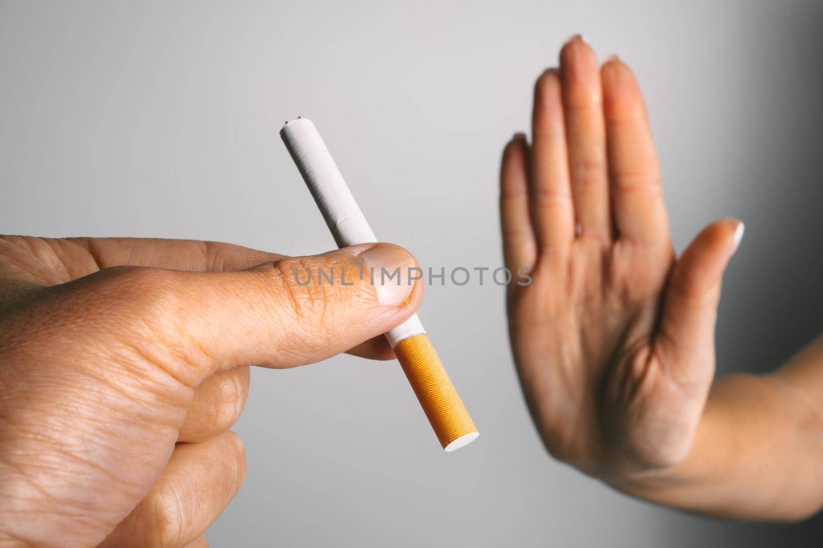 Woman showing stop sign with hand and refusing to take cigarette. No smoking or quit smoking concept. High quality photo