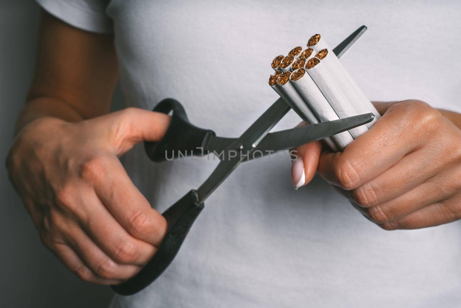Woman cutting with scissors cigarettes. Stop smoking, quit smoking or no smoking concept. Woman refusing tobacco. Quit bad habit. High quality photo