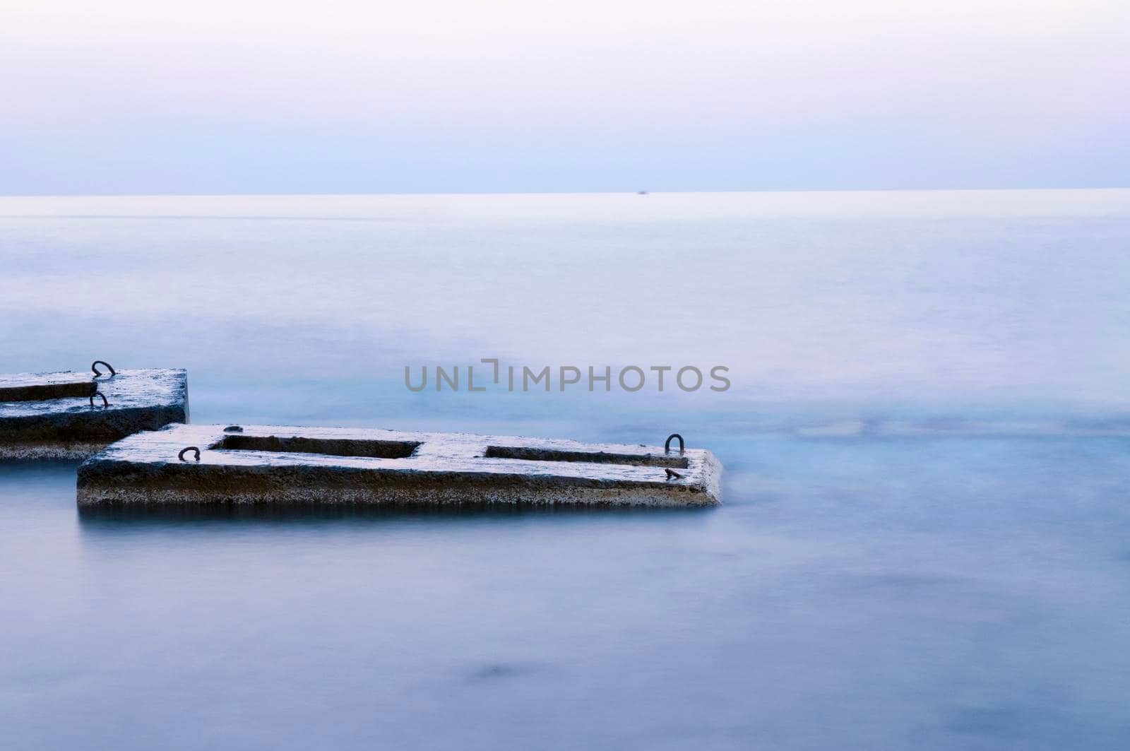 tranquil landscape with concrete structures in sea water at twilight 