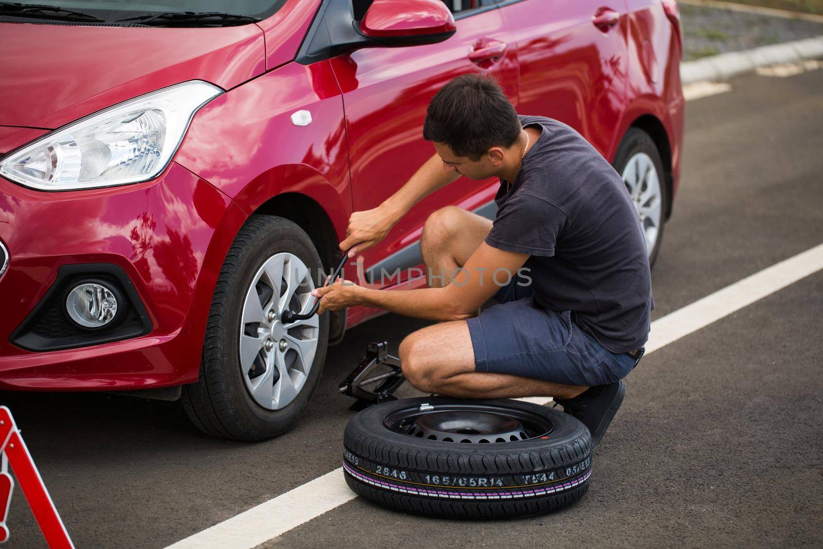 Man repairing car wheel on the road. by StudioPeace