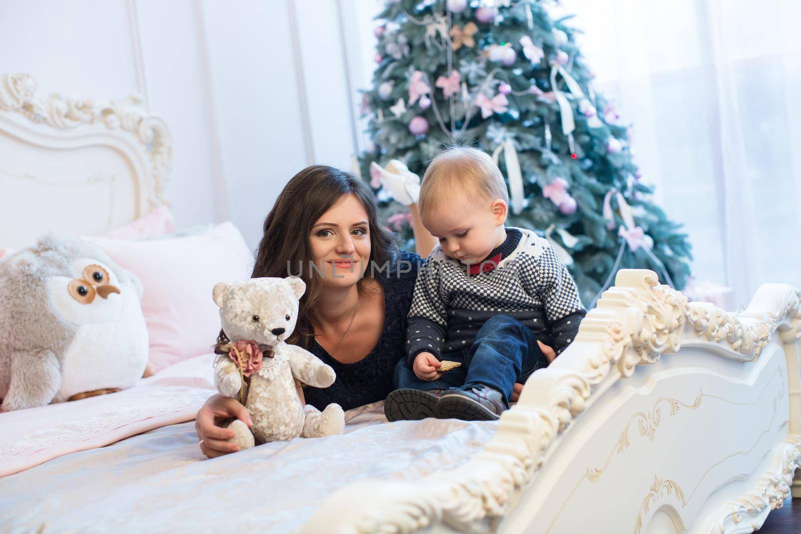 Mother with baby on the bed on the Christmas tree.